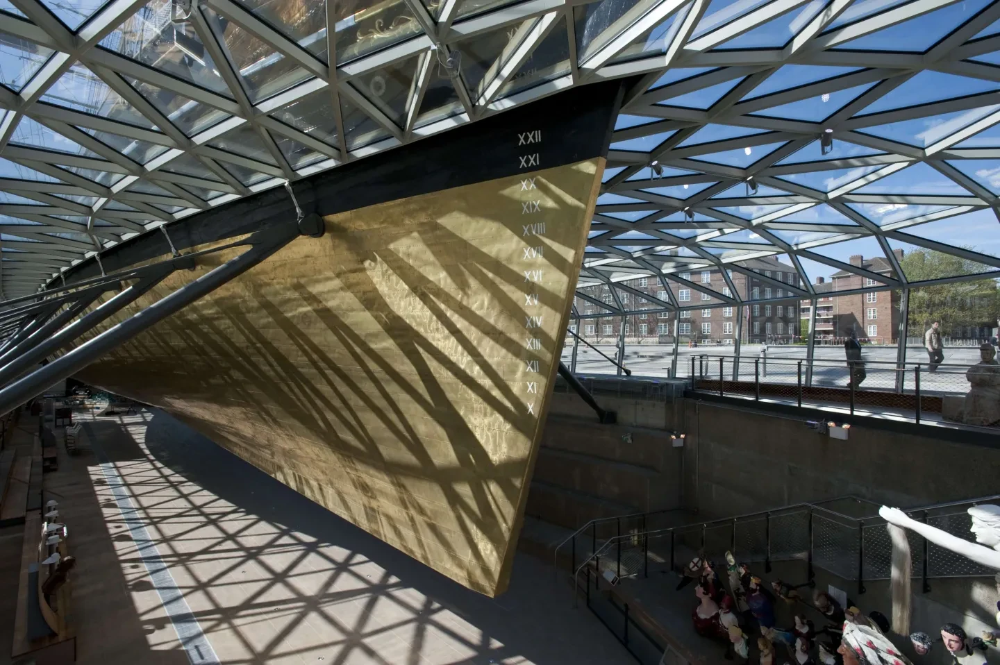 Lattice shadows from the roof of Cutty Sark's enclosure are cast on her copper hull.