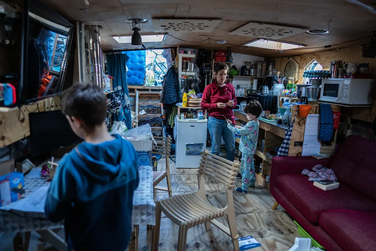 A woman and two children stand in their houseboat