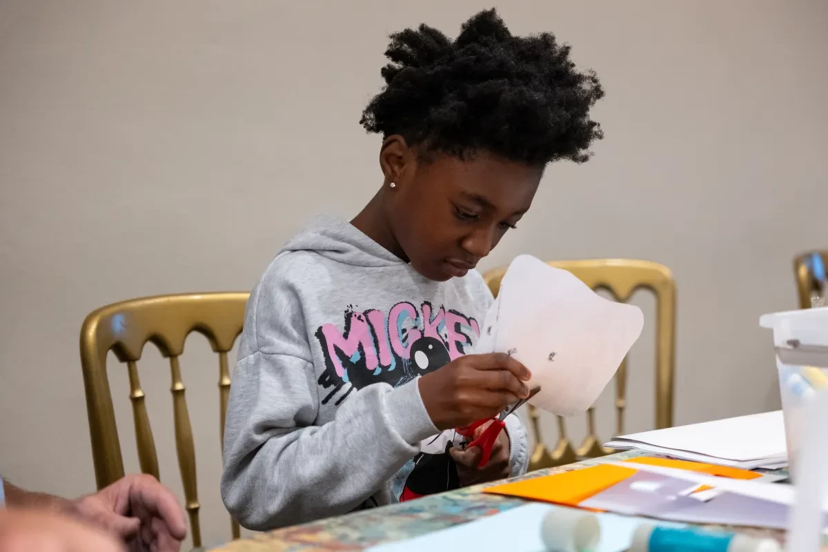 A child cuts out shapes from a piece of paper in a craft workshop