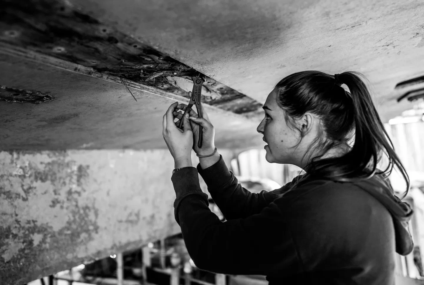 A woman mends the hull of a ship